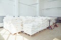 Folded white bags on pallets in factory storage.