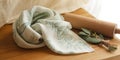 Folded white cloth with green leaf pattern next to rolling pin and herbs fabric Royalty Free Stock Photo
