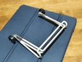 A folded white metal tablet stand placed on a blue textured tablet cover, highlighting a compact and portable design. Royalty Free Stock Photo