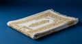 A folded white prayer rug with golden embroidery featuring intricate patterns sits Royalty Free Stock Photo