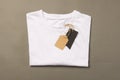 Folded white t shirt with tags with copy space on brown background Royalty Free Stock Photo