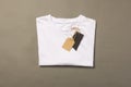 Folded white t shirt with tags with copy space on brown background Royalty Free Stock Photo