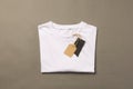 Folded white t shirt with tags with copy space on brown background Royalty Free Stock Photo