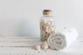 Folded white towel near a bottle with seashells on a white wooden table. Spa and wellness, cotton terry textile Royalty Free Stock Photo