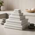 Folded white towels arranged in a neat pyramid on a cream-colored surface. Smooth gray stones are Royalty Free Stock Photo