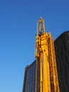 Folded yellow construction crane with gantry strapped to the side waiting to be deployed on an urban building site Royalty Free Stock Photo