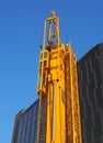 Folded yellow construction crane with gantry strapped to the side waiting to be deployed on an urban building site Royalty Free Stock Photo