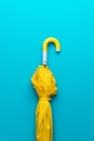 Folded yellow umbrella on turquoise blue background Royalty Free Stock Photo