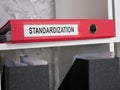 A folder with documents about standardization on a shelf.