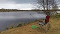 A folding fishing chair, landing net, a towel, bait boxes, a bucket with lure, a cage and feeder rod for bream fishing mounted on Royalty Free Stock Photo