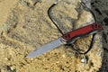 Folding knife stainless blade black red handle travel vacation stone background
