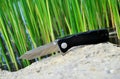 Folding knife stainless steel sharp blade black handle close up still life green background