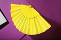 Folding yellow hand fan on purple background Royalty Free Stock Photo