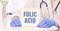 Folic Acid written on a card in doctors hands Royalty Free Stock Photo