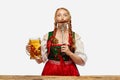 Portrait of waitress wearing a traditional Bavarian or german dirndl holding big mug of beer and sausage as mustache Royalty Free Stock Photo