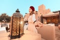 happy woman traveler wearing dress and turban walking through the streets of an old Arab town or village in the middle of