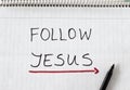 Follow Jesus Christ, handwritten text message with a red arrow showing a way written on a spiral notebook Royalty Free Stock Photo