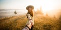 Follow me concept. Couple in love holding hands. Woman in yellow shirt and straw hat holding man by hand going to autumn forest