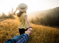 Follow me concept. Couple in love holding hands. Woman in yellow shirt and straw hat holding man by hand