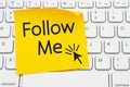 Follow me message on a yellow sticky note on a gray computer keyboard