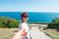 Follow me. Portrait of Cheerful smiling young woman in sunglasses holding man by hand and walking through park trail to the sea. T Royalty Free Stock Photo