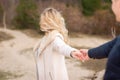 Follow me. Romantic concept. Young caucasian woman with long blonde hair outdoors holding guy`s hand.Traveling together