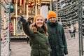 Follow me shot of a young attractive loving couple at the Christmas market in winter. Man and woman wearing orange hats and green