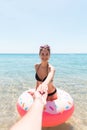 Follow me Vacation concept. girlcalls to swim in the sea and waves her hand. Girl relaxing on inflatable ring in the sea. Summer