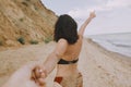 Follow me. Woman leading her man, holding hands on beach. Couple in love on summer vacation or honeymoon. Young woman with sandy