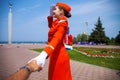 Follow Me, Young stewardess dressed in official red uniform of Airlines, Summer park outdoors