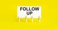 Follow up, message on white card on yellow background Royalty Free Stock Photo