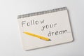 Follow your dream motivation notice. Notepad and pen on white background