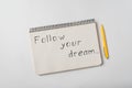 Follow your dream written on notebook . Notepad and pen on white background