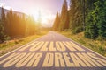 Follow your dreams text written on road in the mountains