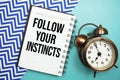 Follow Your Instincts text written on notepad with alarm clock Royalty Free Stock Photo