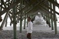 Folly Beach South Carolina, February 17, 2018 - white male walking under beach pier Royalty Free Stock Photo
