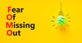 FOMO fear of missing out symbol. Concept words FOMO fear of missing out on beautiful yellow background. Green light bulb icon. Royalty Free Stock Photo