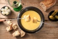 Fondue from melted cheese with bread on long forks, pickles and wine on a rustic wooden table, traditional new year dish from Royalty Free Stock Photo