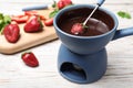 Fondue pot with chocolate and strawberries on white wooden table. Royalty Free Stock Photo