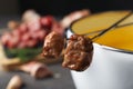 Fondue pot and forks with cooked meat on table Royalty Free Stock Photo