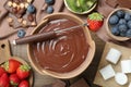 Fondue pot with melted chocolate, marshmallows, fresh kiwi, different berries and fork on wooden table, flat lay Royalty Free Stock Photo