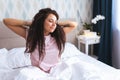 Font view of young woman waking up in early morning sitting on bed with whitesnow linen and sretch her arms and body Royalty Free Stock Photo