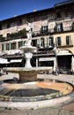 Fontana Madonna Verona, in the foreground with the frescoed and sunlit facades of ancient buildings in Piazza delle Erbe in Verona Royalty Free Stock Photo