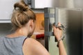 Food addiction and gluttony concept - woman cuffed to the handle looking inside the fridge