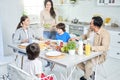 Food for all. Happy latin family having dinner together at home. Cheerful woman smiling while serving salad for her