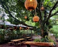 Food area in a camp surrounded by lush vegetation, trees decorated with wicker lamps Royalty Free Stock Photo