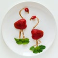 Food art creative concept. Flamingos on white plate. Strawberry, chocolate and mint composition