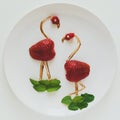 Food art creative concept. Flamingos on white plate. Strawberry, chocolate and mint composition. Top view.