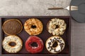 Assortment of donuts on wooden tray with dark plate and small fork and napkin