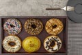 Assortment of donuts on wooden tray with napkin fork and small plate